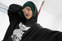 Load image into Gallery viewer, goth girl with green hair wearing black hoodie with three eyed mutant cat and armoured battle monster alt fashion design named THE CAT & THAT