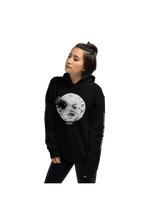 Lade das Bild in den Galerie-Viewer, Black unisex hoodie with alternative fashion rocket in moon&#39;s eye from George Melliés&#39; film Trip to the Moon with the original French title Voyage Dans La Lune 1902
